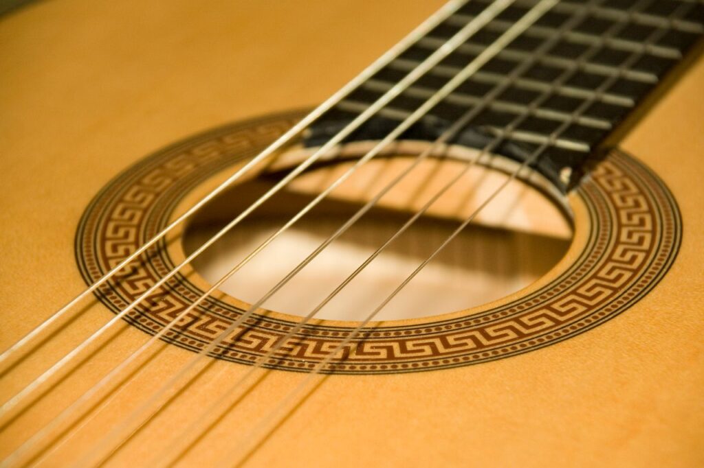 Detailed close-up of classical acoustic guitar strings and soundhole with intricate rosette.