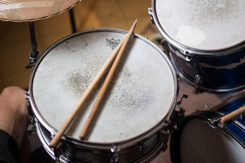 Detailed image of drumsticks resting on a snare drum in a music studio.