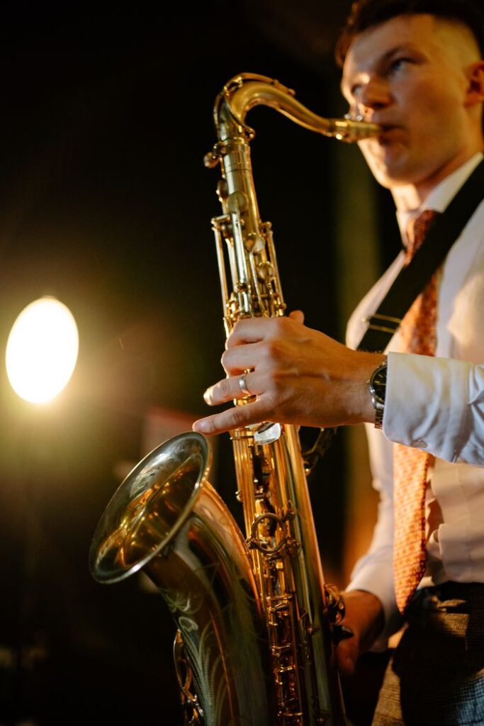 Saxophonist passionately playing on stage during a live concert under warm lighting.